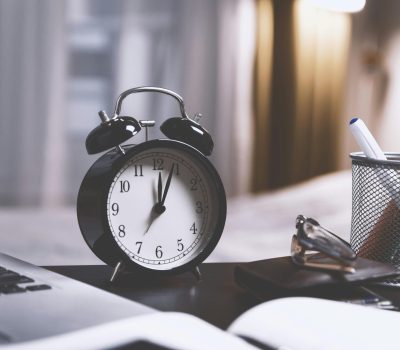 Image of a clock on a table that is also covered by books